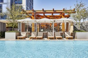 a swimming pool with lounge chairs and umbrellas at Conrad Los Angeles in Los Angeles