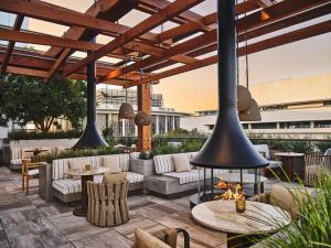 an outdoor patio with couches and tables and pendant lights at Conrad Los Angeles in Los Angeles