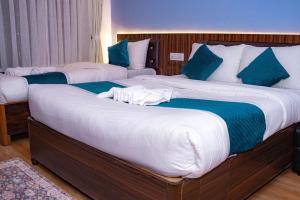 two beds in a hotel room with blue and white sheets at Umai Garden Resort in Jogīkuti
