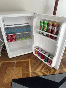 an open refrigerator with drinks and cans of soda at Pousada Jangarelli in Guaíra