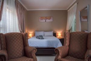 a bedroom with a bed and two chairs at Rusty Estate - Self Catering in eMalahleni