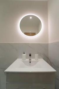 a bathroom with a white sink with a round mirror at Foundry Farm Apartment in Hexham +17 photos