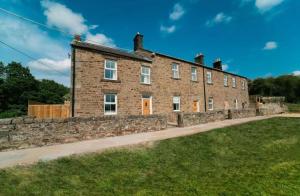 a large brick building with a stone wall at Foundry Farm Apartment in Hexham