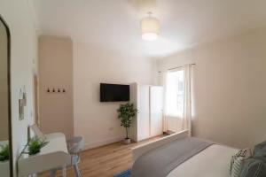 a white bedroom with a bed and a tv at Foundry Farm Apartment in Hexham