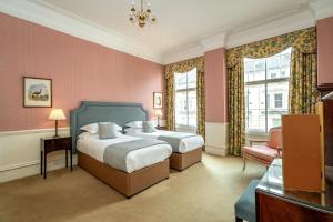 two beds in a room with pink walls and windows at No1 The Mansions By Mansley in London