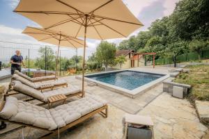 a man standing next to a swimming pool with an umbrella at Forest by Leni - National Park Salt Pool Villa in Beočin