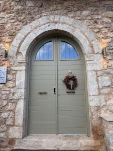 a door with a wreath on it in a stone wall at Miglari in Stemnitsa