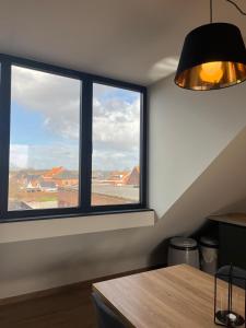 a room with two windows and a table and a lamp at Bomaison charmant landelijke studio in Aalter