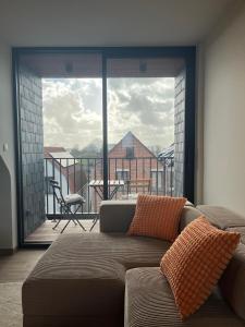 a living room with a couch and a view of a balcony at Bomaison charmant landelijke studio in Aalter