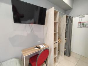 a room with a tv on a wall with a red chair at Hôtel Claridge's in Menton