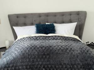 ein Bett mit grauer Bettdecke und Kissen in der Unterkunft Deich Kate in Wurster Nordseeküste