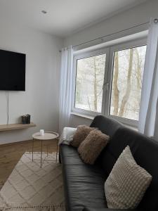 ein Wohnzimmer mit schwarzem Sofa und einem Fenster in der Unterkunft Deich Kate in Wurster Nordseeküste