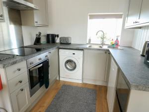 a kitchen with a washing machine and a sink at Bwthyn in Moelfre