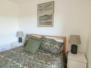 a bedroom with a bed and a picture on the wall at Bwthyn in Moelfre