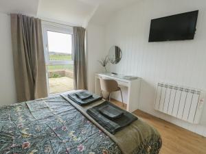 a bedroom with a bed and a desk and a window at Bwthyn in Moelfre