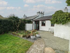 a small white house with plants in a yard at Bwthyn in Moelfre