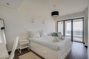 a white bedroom with a bed and a window at luxury Plazza Sea view in Costa da Caparica