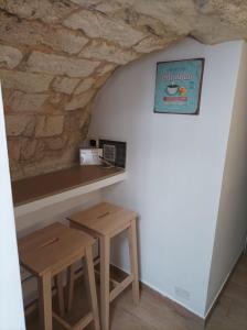 a bar with two wooden stools and a stone wall at Il sottano borgo antico in Bari