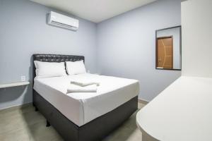 a white bedroom with a bed and a mirror at Pousada Recanto do Sol BF in Baía Formosa