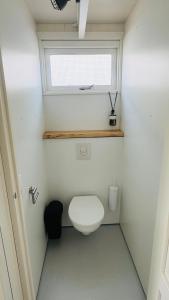 a small bathroom with a toilet and a window at SandCsleep in Katwijk