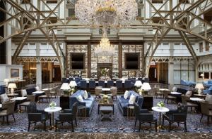 a lobby with a chandelier and tables and chairs at Waldorf Astoria Washington DC in Washington, D.C.