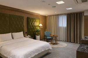 a bedroom with a bed and a table and a chair at Zenith Tourist Hotel in Bucheon