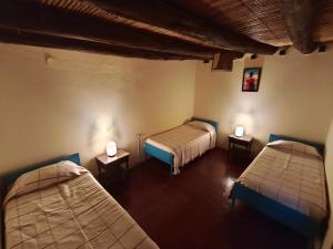 a room with two beds and two lamps on tables at Posada Las Piedras in Tilcara