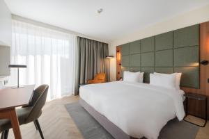 a hotel room with a large white bed and a desk at Radisson Blu Hotel, Montpellier in Montpellier +59 photos