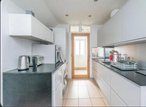 a kitchen with white cabinets and a black counter top at Soofi House in Sheffield