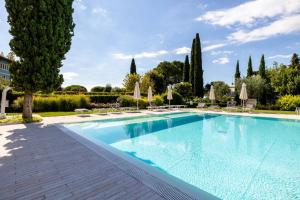 a large swimming pool with chairs and trees at Corte Fasanella 25 - Gardagate in Toscolano Maderno