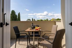a table with chairs and a glass of wine on a balcony at Corte Fasanella 25 - Gardagate in Toscolano Maderno