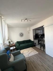 a living room with a green couch and a kitchen at Homewood - entire property for 6 people - 4 adults maximum - in village 10 min from Disneyland Paris & TGV RER A in Montry