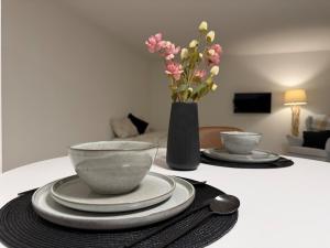 a table with plates and bowls and a vase with flowers at Studio Lakeview in Ennetbürgen