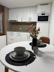 a white kitchen with a table with plates and flowers at Studio Lakeview in Ennetbürgen +1 photo