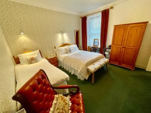 a bedroom with two beds and a chair in it at Rockhill Guest House in Moffat