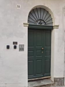 a green door in a white building with an arch at Il Nido della Piazzetta in Saluzzo