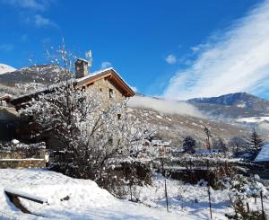 a house in the snow in front of a mountain at Le Petit Soleil in Saint-Christophe