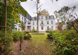a large white house with a garden in front of it at Zenao Appart'hôtels Saint-Mandé in Saint-Mandé