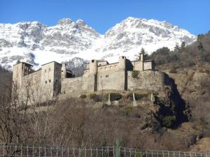 a castle on a hill with snow covered mountains at Le Petit Soleil in Saint-Christophe