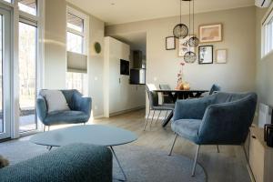 a living room with blue chairs and a table at Chalet Bosrijk in Haarle