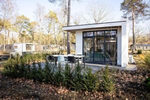 a small white house with a table and chairs at Chalet Bosrijk in Haarle