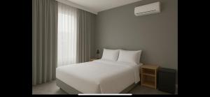 a bedroom with a white bed and a window at Pousada Catarina in Biguaçu