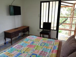 a bedroom with a bed and a desk and a window at Cabañas en el Bosque in Borrero Ayerbe