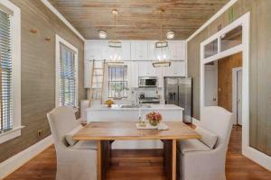 a kitchen with a wooden table and white cabinets at Rustic Luxury - As Seen on "Restoring Galveston" TV Show in Galveston +14 photos