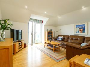a living room with a couch and a tv at Maelog, 14 Tides Reach in Rhosneigr