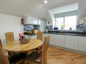 a kitchen with a table and chairs and a clock at Maelog, 14 Tides Reach in Rhosneigr