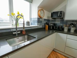 a kitchen with a sink and a clock on the wall at Maelog, 14 Tides Reach in Rhosneigr +21 photos