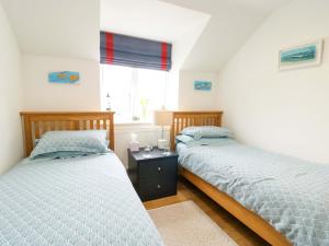 two twin beds in a bedroom with a window at Maelog, 14 Tides Reach in Rhosneigr