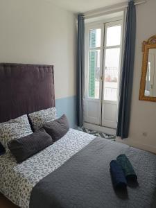 a bedroom with a bed with two pillows and a window at Chambre Lumineuse avec Balcon - Cuisine Partagée & Salle de Bain Privée in Lourdes
