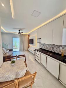 a living room with a table and a kitchen at Diamante dos Ventos Duplex com Piscina Cumbuco in Caucaia